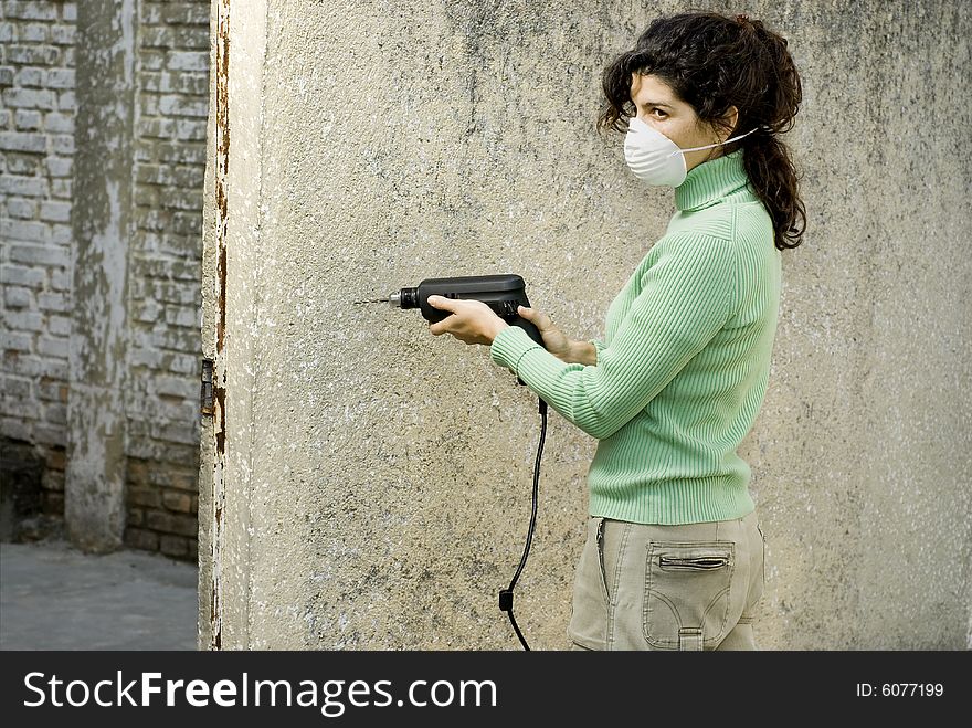 Woman wearing a mask using an electric sander. Horizontally framed photo. Woman wearing a mask using an electric sander. Horizontally framed photo.