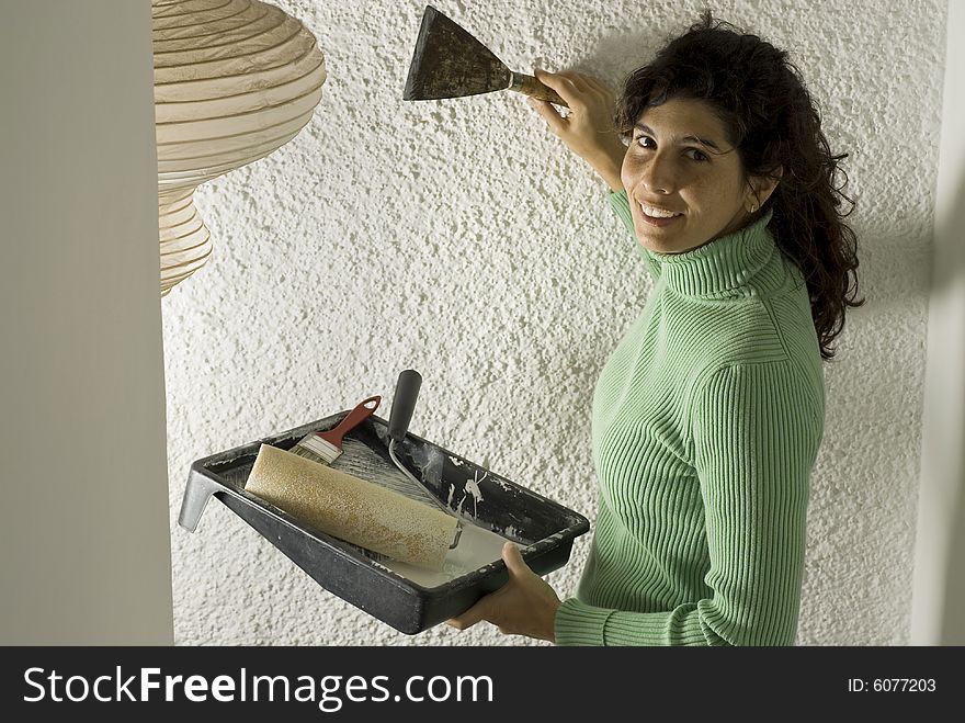 Woman smiles as she holds a paint tray and a paint scraper. Vertically framed photo. Woman smiles as she holds a paint tray and a paint scraper. Vertically framed photo.