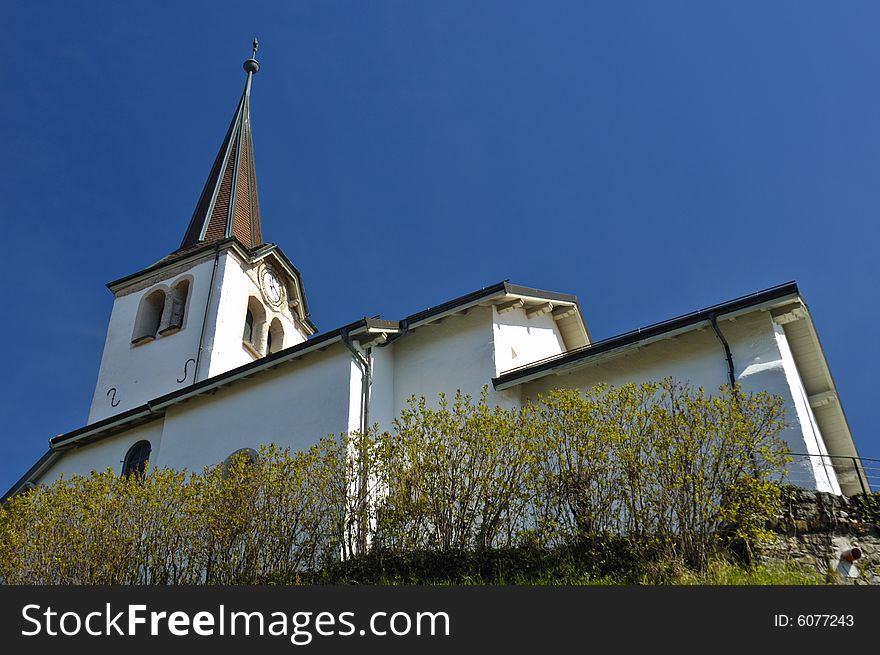 The church in the Swiss wine-growing village of Fechy, from a low viewpoint. Space for text in the clear blue sky. The church in the Swiss wine-growing village of Fechy, from a low viewpoint. Space for text in the clear blue sky.