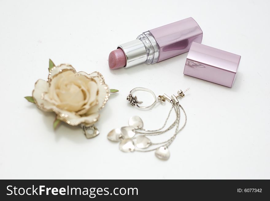 Lipstick and ear ring on white
