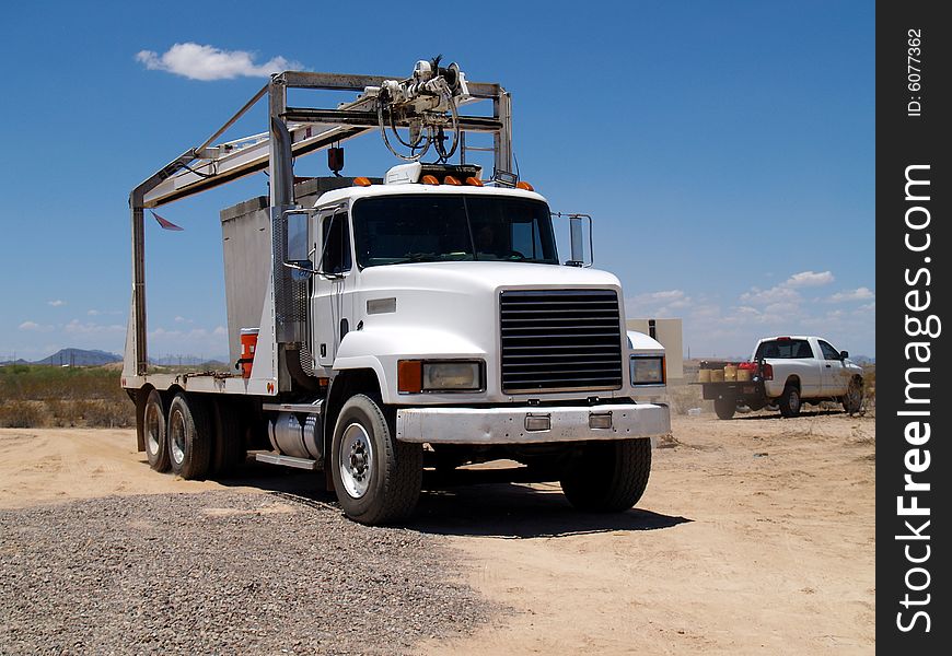 Mack truck at a construction site with a smaller work truck in the background. Horizontally framed photo. Mack truck at a construction site with a smaller work truck in the background. Horizontally framed photo.