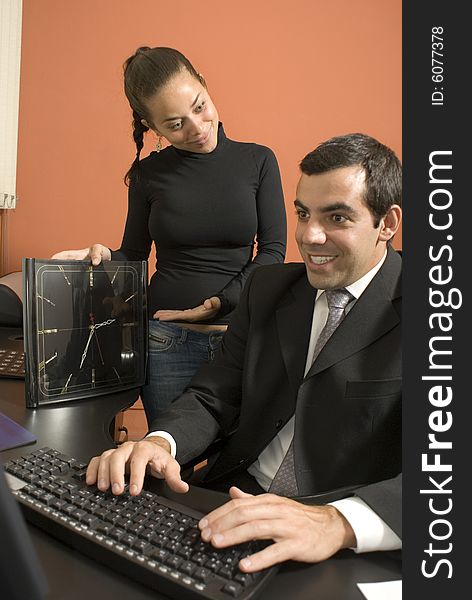 Businessman typing as his secretary looks on. Vertically framed photo. Businessman typing as his secretary looks on. Vertically framed photo.