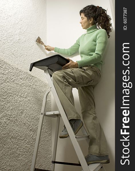 Woman standing on a ladder uses a paint scraper. Vertically framed photo. Woman standing on a ladder uses a paint scraper. Vertically framed photo.