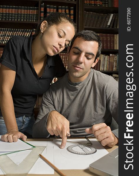 Young couple with their heads pressed together work on paperwork. Vertically framed photograph. Young couple with their heads pressed together work on paperwork. Vertically framed photograph.