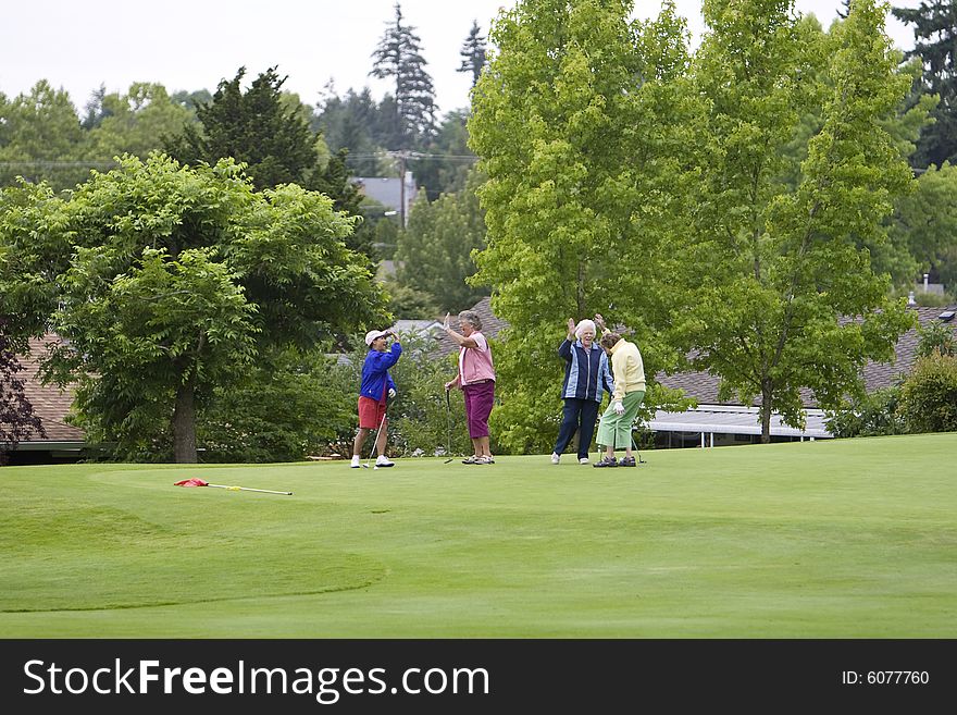 Group of four women slap high five while playing golf. Horizontally framed photo. Group of four women slap high five while playing golf. Horizontally framed photo.