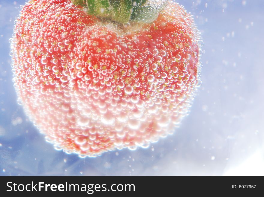 A fresh strawberry being submerged in water with bubbles. A fresh strawberry being submerged in water with bubbles.