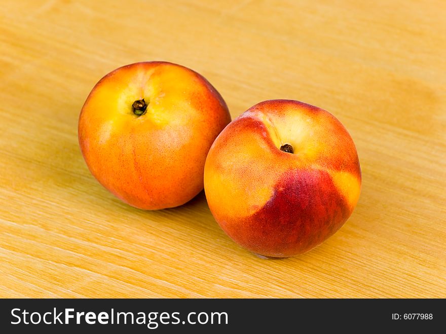 Two ripe nectarines on the wooden background.