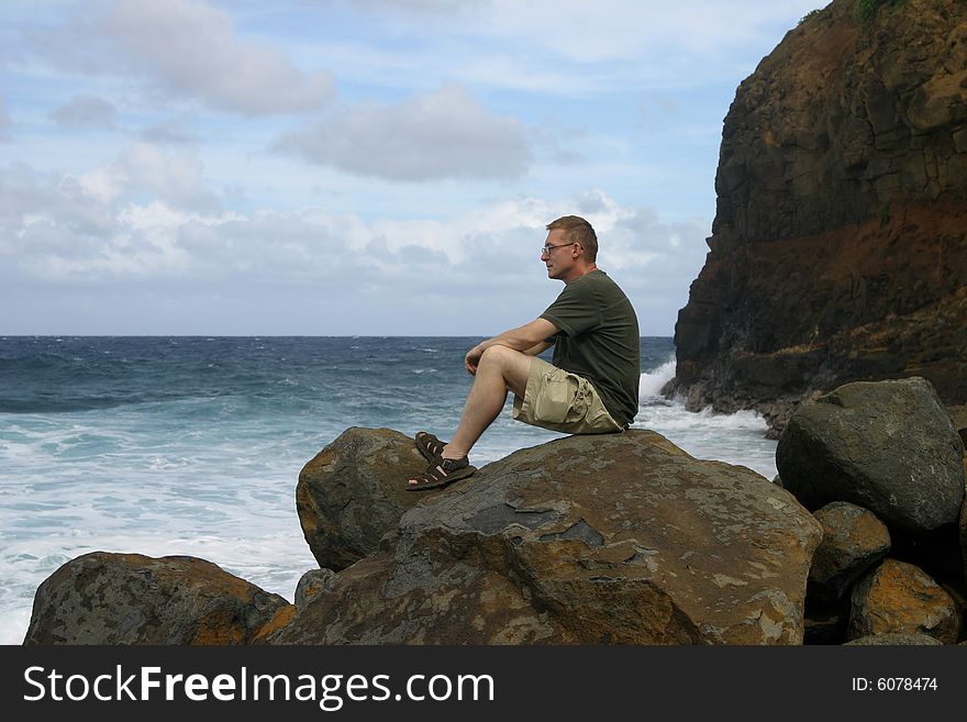 Lonely man sitting on the rock on the coast of Pacific Ocean in Hawaii. Lonely man sitting on the rock on the coast of Pacific Ocean in Hawaii.