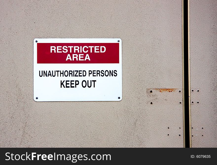 Warning sign on wall restricting access to unauthorized persons. Warning sign on wall restricting access to unauthorized persons.