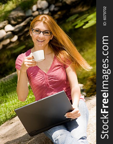 Beautiful young student using laptop and drink coffee in natural environment. Beautiful young student using laptop and drink coffee in natural environment.