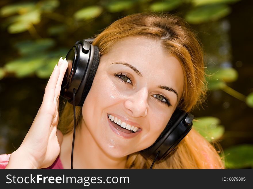 Beautiful young woman listen music by headphones in natural environment. Beautiful young woman listen music by headphones in natural environment.