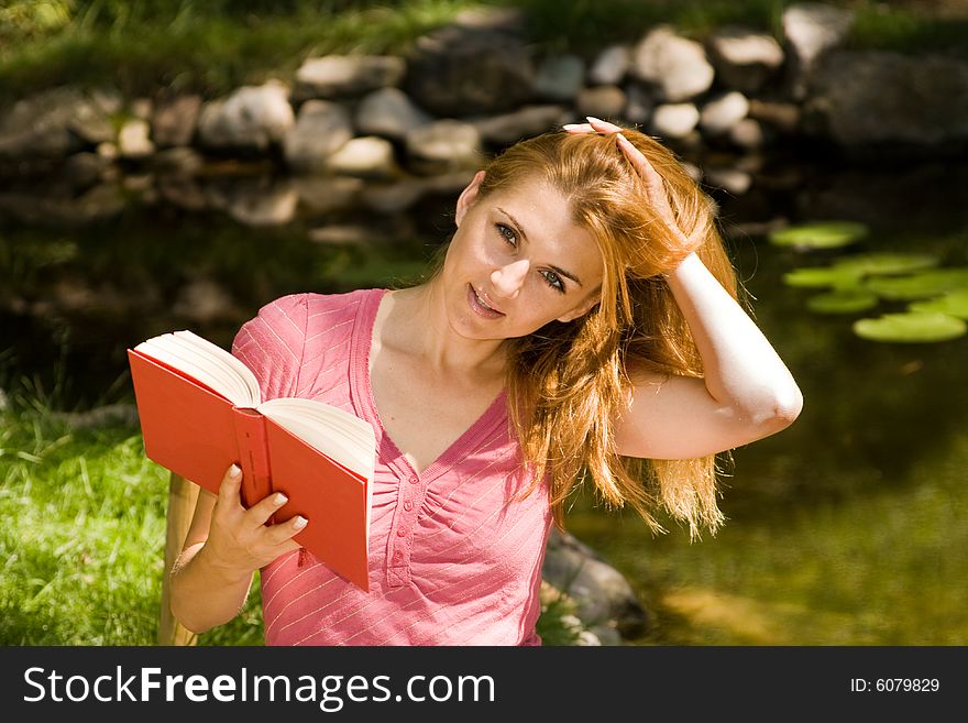 Beautiful young student reading book in natural environment. Beautiful young student reading book in natural environment.