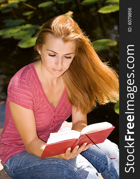 Beautiful young student reading book in natural environment. Beautiful young student reading book in natural environment.