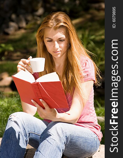 Beautiful young student reading book and drink coffee in natural environment. Beautiful young student reading book and drink coffee in natural environment.