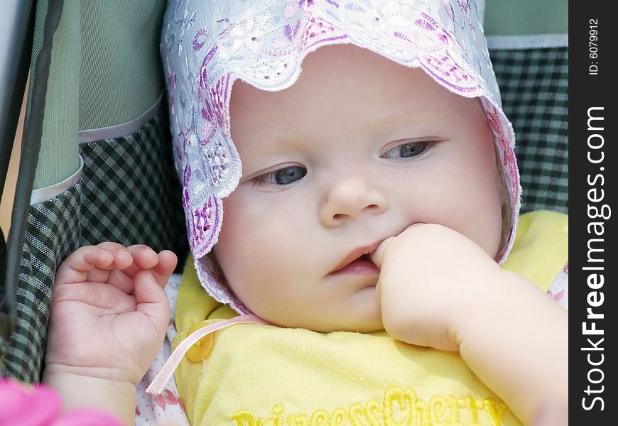 Portrait of 6 month baby holding finger at mouth