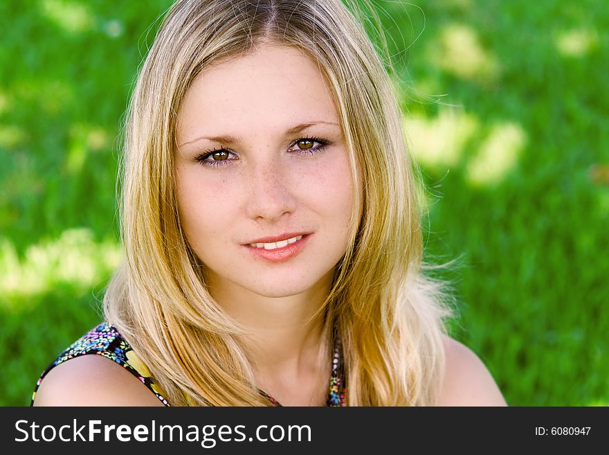 Blond girl smiling against a background green grass