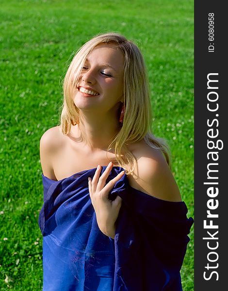 Blond girl laughter against a background green grass