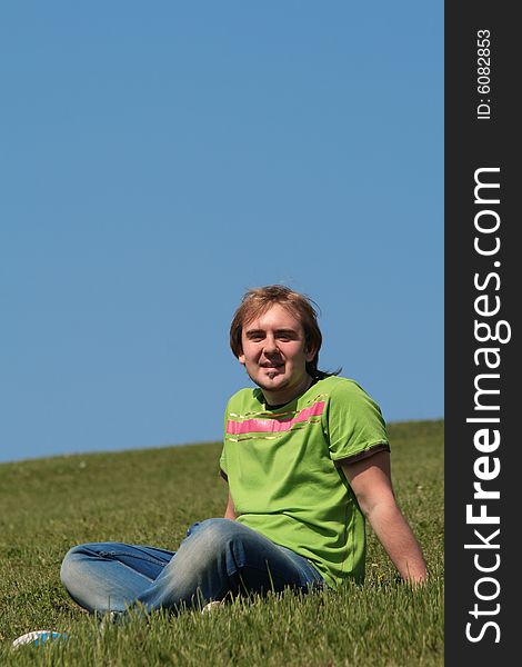 Happy young man sitting on the grass