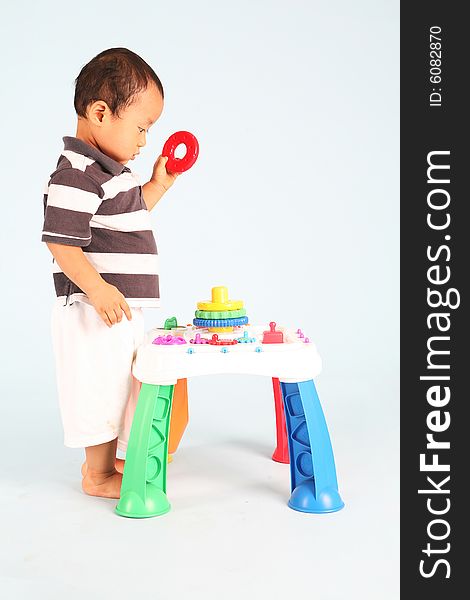 An unhappy asian toddler playing with his toy alone. An unhappy asian toddler playing with his toy alone