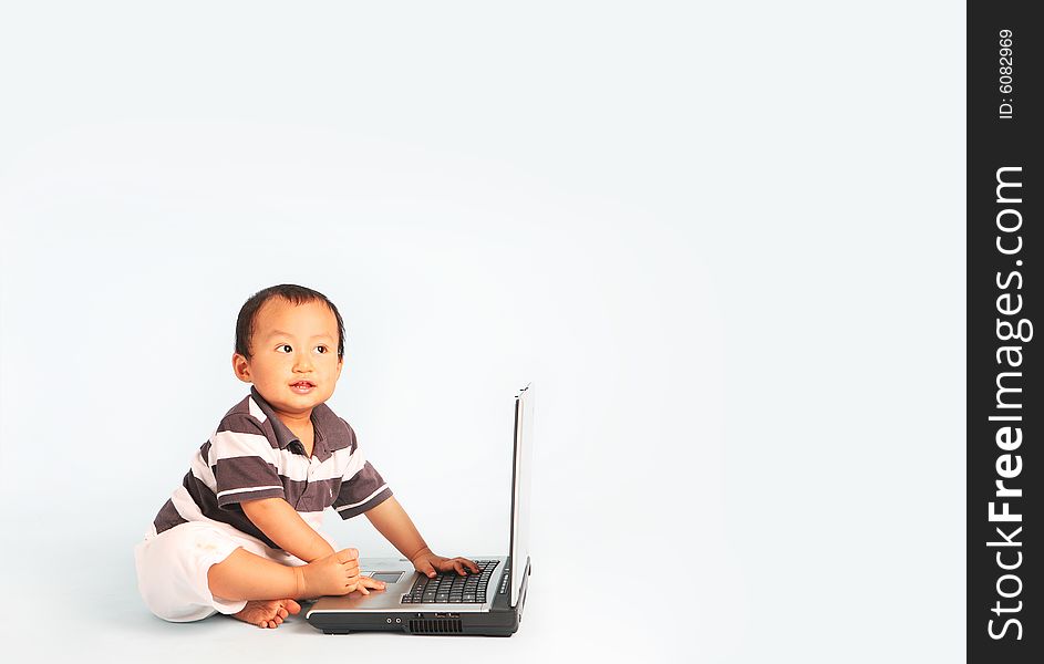 A happy toddler using a laptop computer. Eyes are looking up