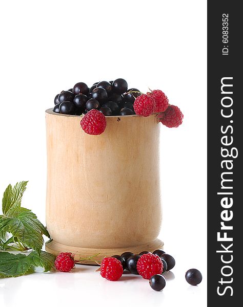 Black currant and raspberries in wood cup isolated on white