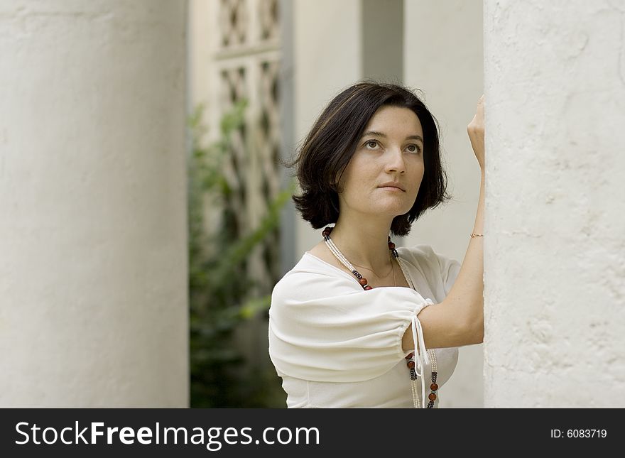Portrait of pretty woman standing near white column
