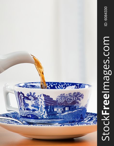 Pouring tea into a blue patterned teacup. Pouring tea into a blue patterned teacup