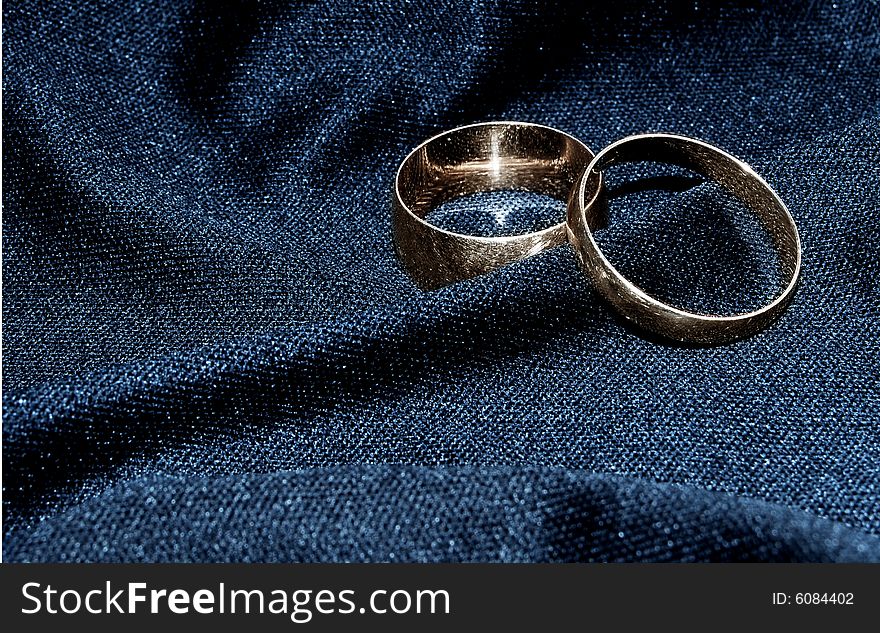 Two brilliant wedding rings on a black fabric.