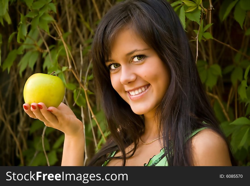 The brunette with an apple on a background of foliage