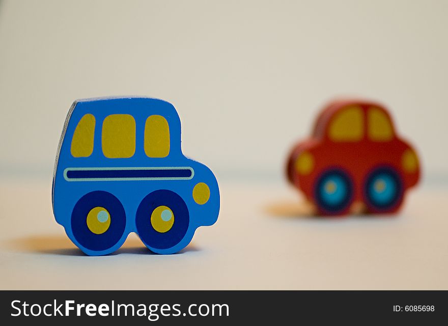 Two mini wooden cars toy, one blue one red, creating an impression of movement. Two mini wooden cars toy, one blue one red, creating an impression of movement.