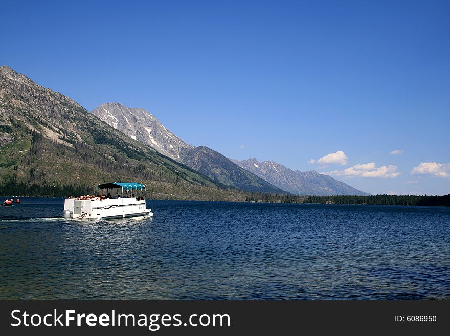 Tourist ship is going on the lake surrounding by mountains. Tourist ship is going on the lake surrounding by mountains