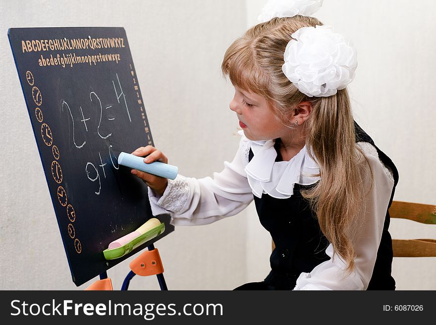An image of nice little girl in shool writing on chalkboard. An image of nice little girl in shool writing on chalkboard.