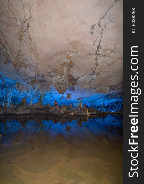 Water-eroded Reed Flute Cave with its stalactites, stone pillars and rock formations created by carbonate deposition, illuminated by colored lighting. Guilin, China