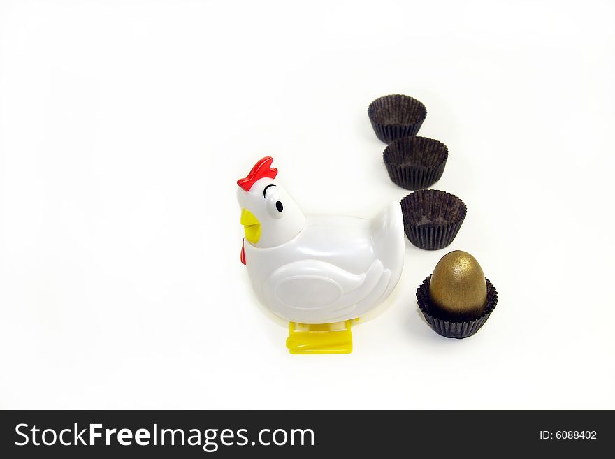 A hen by golden egg inside a chocolate paper wrapper, like she just lay the egg and is going to the next wrapper for more. A hen by golden egg inside a chocolate paper wrapper, like she just lay the egg and is going to the next wrapper for more