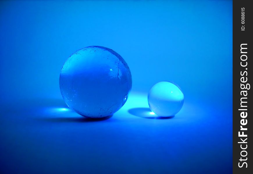 Two blue glass balls on blue background