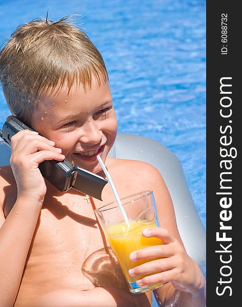 Boy speaks by phone and drinks orange juice