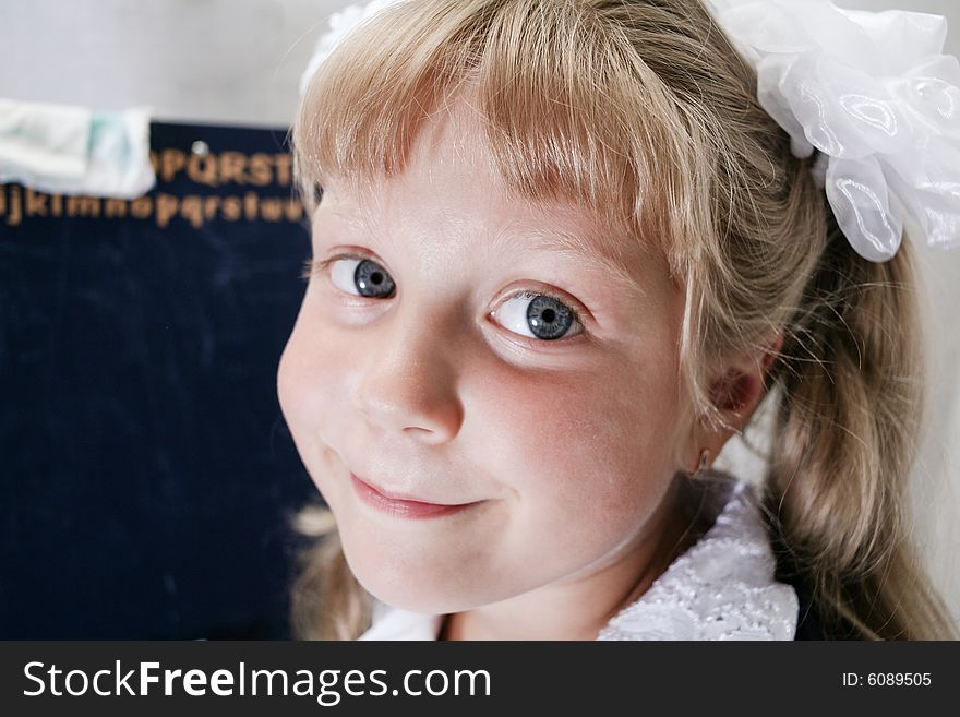 Little girl with white bow near the school boards