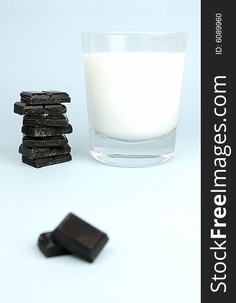 Dark chocolate and a glass of milk isolated against a blue background