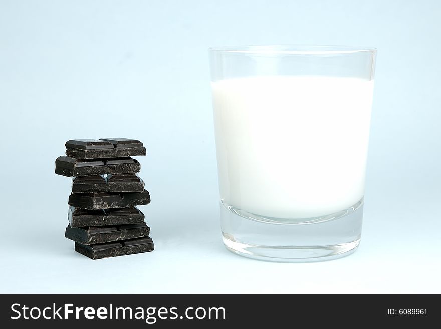 Dark chocolate and a glass of milk isolated against a blue background