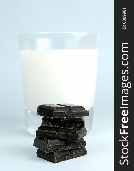 Dark chocolate and a glass of milk isolated against a blue background