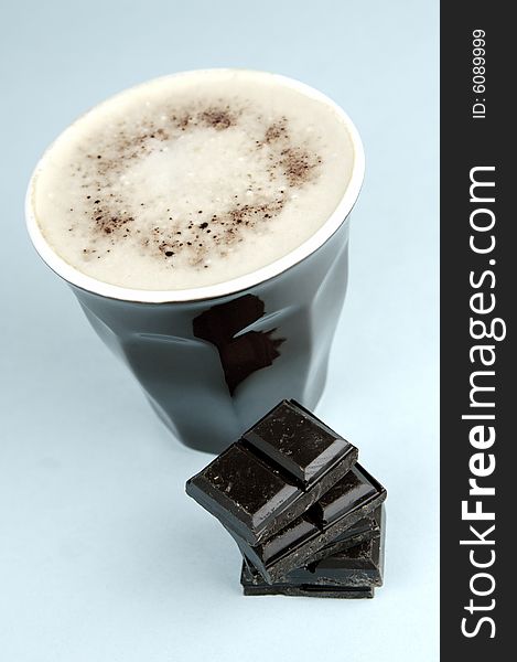 Dark chocolate and a cappuccino isolated against a blue background