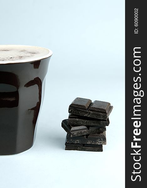 Dark chocolate and a cappuccino isolated against a blue background