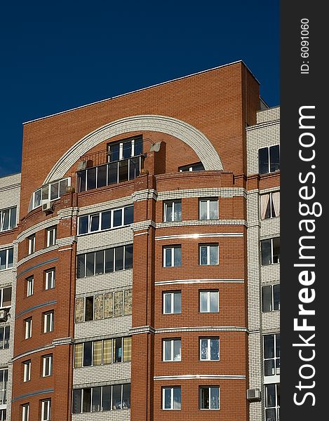 High multistory house of red and white bricks on sky background