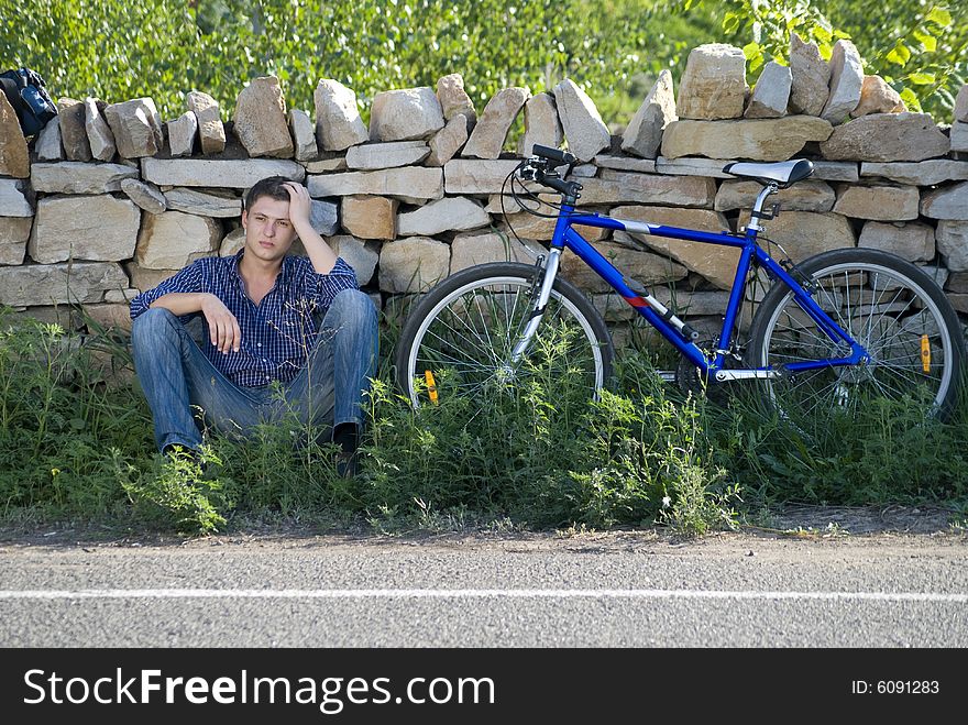 A young man with a bicycle in the green grass. A young man with a bicycle in the green grass