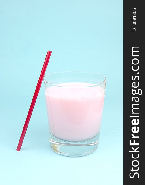 A strawberry flavoured glass of milk isolated against a blue background. A strawberry flavoured glass of milk isolated against a blue background