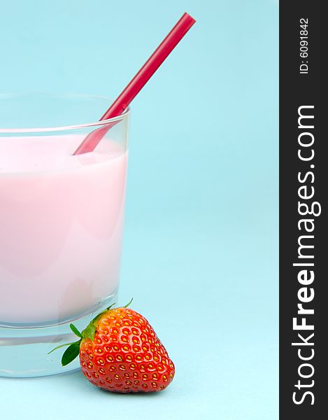 A strawberry flavoured glass of milk isolated against a blue background. A strawberry flavoured glass of milk isolated against a blue background