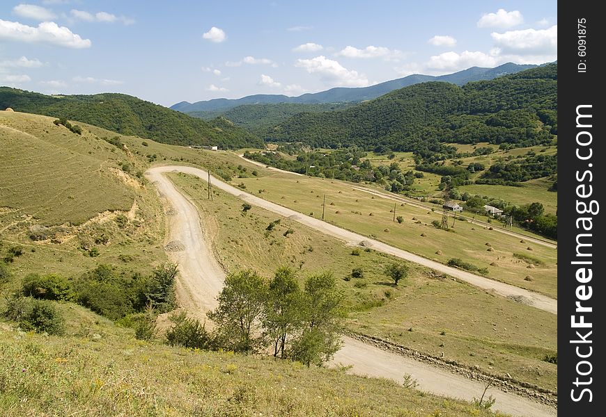 Sandy hairpin road in gorgian mountains. White clouds blue sky. Sandy hairpin road in gorgian mountains. White clouds blue sky.