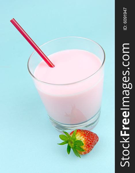 A strawberry flavoured glass of milk isolated against a blue background. A strawberry flavoured glass of milk isolated against a blue background