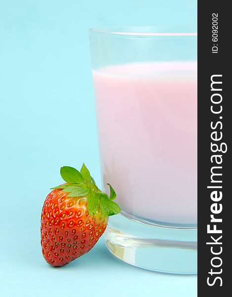 A strawberry flavoured glass of milk isolated against a blue background. A strawberry flavoured glass of milk isolated against a blue background