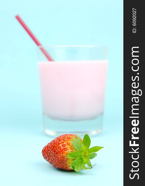 A strawberry flavoured glass of milk isolated against a blue background. A strawberry flavoured glass of milk isolated against a blue background